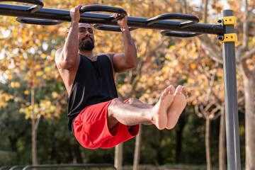Obraz premium african american athlete boy does calisthenics fitness exercises on bars in park