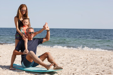 Allegra famiglia composta da padre, madre e figlia si diverte giocando con con una tavola da surf...