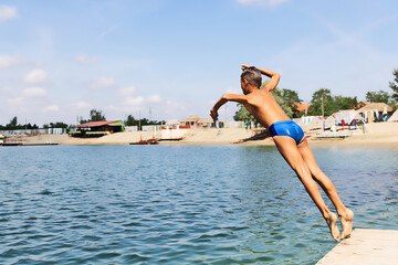 Small boy jumping in the water from a pier.