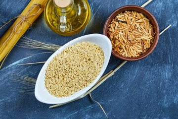 Various uncooked pasta with a bottle of oil, flour