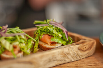 Smoked salmon bruschetta with cucumber and lettuce shavings. Homemade toasts with smoked salmon and garniture