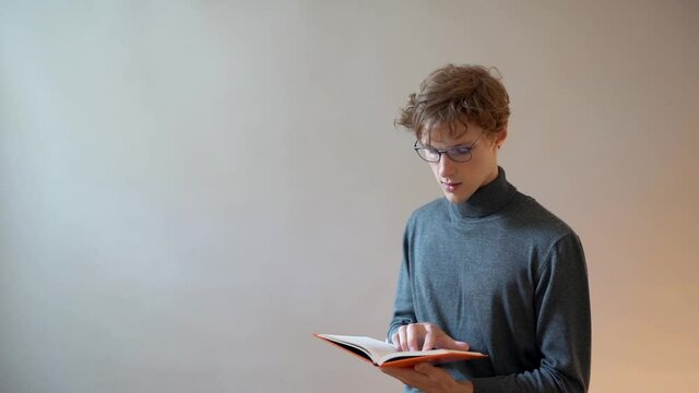 An angry young man hits himself on the head with a book