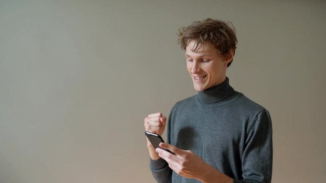 The young guy receives a joyful message on his smartphone