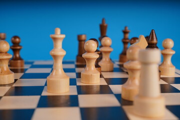 Close-up of chess on a blue background. Wooden chess pieces. Concept: the Board game and the intellectual activities