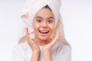 Adorable pretty teen girl in spa towel using face cream isolated over white background