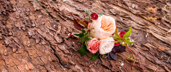 Elegant wedding floral bouquet of pink roses lies on the bark of a tree