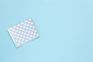 Health care concept. Blister pack with white pills on a blue background. Copy space.