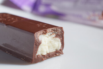 a half-bitten chocolate bar with filling lies on the table macro photo blurred background