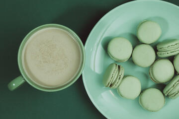 A green cup with coffee next to green macarons. Green cup and green plate. Spring breakfast 