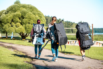 Obraz premium Women carry large dark backpacks and oars. water sports competition concept