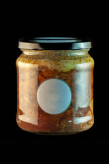 A glass jar with an eco-friendly stew of dark meat on a black background, with a black lid and a small round label in the middle.