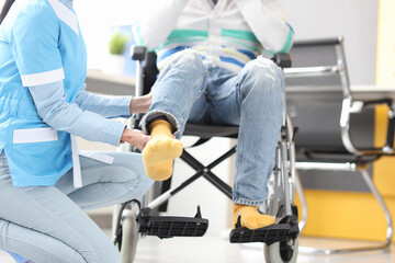 Rehabilitation doctor helping to lift leg of patient in wheelchair closeup
