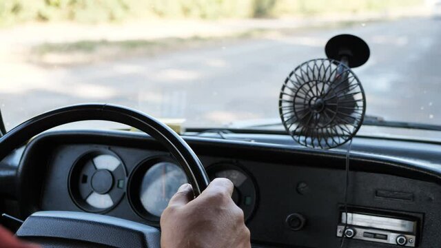 male hands on the steering wheel of an old, vintage, retro car. View of the road through the car windshield.