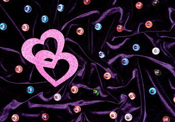 Two pink hearts and multi-colored glass balls on purple velvet. Valentine's day concept.