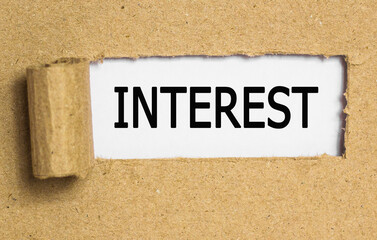 Obraz premium The text INTEREST . behind torn brown paper. Business Concept image