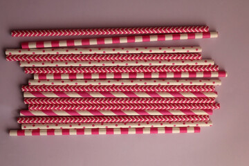 Pink and white paper straws on pastel pink background. Top view.