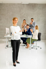 Mature business woman standing in the office in front of her team