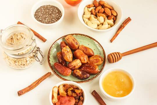 Ingredients for a healthy breakfast, dates, nuts, chia seeds, oatmeal, honey, dry fruit, almonds, cashew nuts on white background. The concept of natural organic food . Flat lay, stock photo