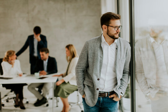 Handsome young business man standing confident in the office and looking trough window