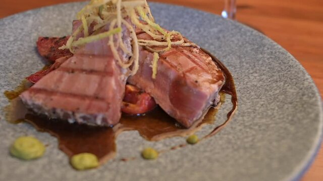 Tuna fillet on a parrilla with rostized jitomate in marmol plate. Tuna fillet and red wine glass