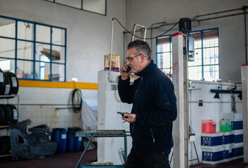 MECHANIC IN HIS WORKSHOP TALKING ON THE PHONE