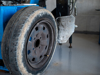 MECHANIC IN HIS WORKSHOP FIXING CAR WHEEL IN MACHINE