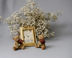Valentines day gift idea. Golden photo frame and figurines of teddy bears with red bouquets. Cute present concept.