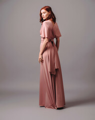 Bridesmaid's look in dust pink. Young ginger woman in summer transformer evening dress and high...