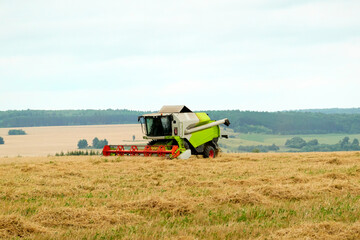 Obraz premium Agricultural landscape. A wheat field with a working combine harvester. Selective focus.