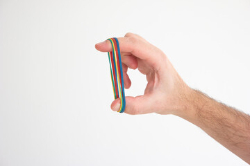Multiple colored rubber bands stretched around Caucasian male hand fingers isolated on white