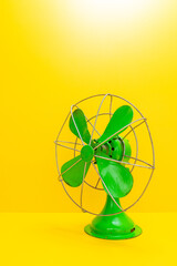 Old green electric fan on yellow background