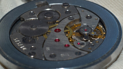 The intricate mechanism with gears of an old winding clock is shot close-up, macro shot