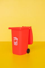 Red garbage container on yellow background