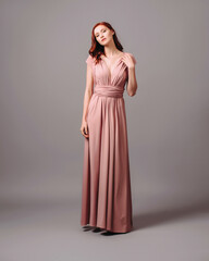 Gorgeous salmon transformer dress. Beautiful sexy silk evening gown with deep neckline and shoulder straps. Studio touching portrait of young ginger woman. Bridesmaid's fashionable look.