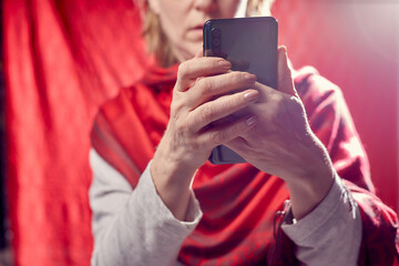 Portrait of a middle-aged woman with cell phone on a white background. Unprofessional female model doing selfie in the room or in the Studio.