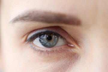 Womans eye with permanent eyelid and eyebrow makeup closeup
