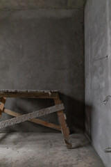 Home improvement. A dirty construction staircase in an empty room with gray concrete walls