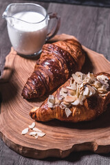 Croissants, milk and coffee on a wooden table in a low key. The concept of traditional breakfasts and delicious food