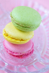 Vertical format of colorful french macarons one on top of each other on translucent glass plate. Traditional dessert