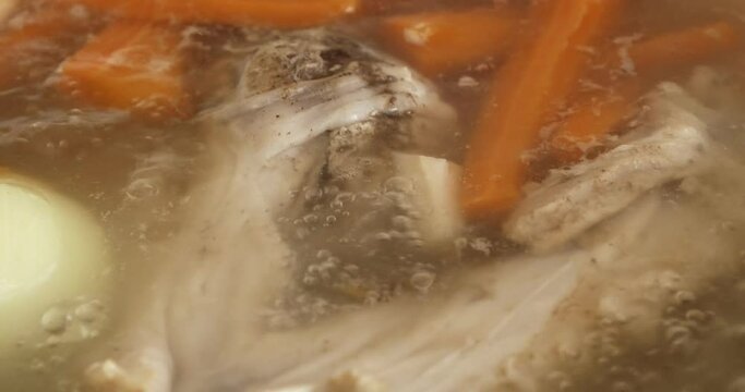 Boiling broth with meat and vegetables close-up. Soup cooking.