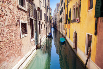 Fototapeta na wymiar Boats rest in a small canal among colorful facades, Venice, Italy