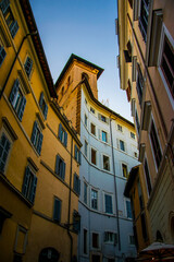 Fototapeta na wymiar Una estrecha calle romana con sus edificios de colores anaranjados pastel