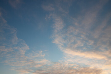 Naklejka na ściany i meble Clouds painted by the setting sun against the blue sky
