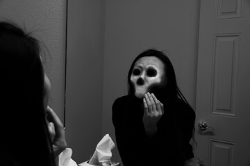 A woman sees herself as skull in the mirror. 