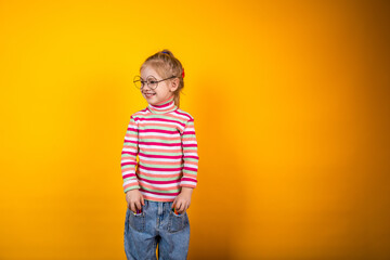 Bright child with colorful markers in his pockets, standing on a yellow background