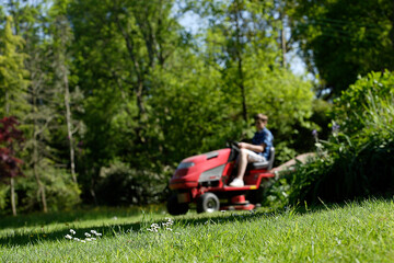 Fototapeta na wymiar A boy on a ride on mower in a garden.