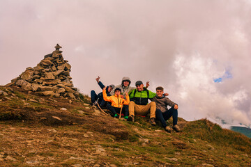 A group of tourists are sitting smiling on top of the mountains of the Montenegrin ridge, Mount Rebra is one of the peaks of the Carpathian mountains.