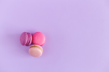 Tasty french macarons on a violet pastel background. Pink and violet macarons.