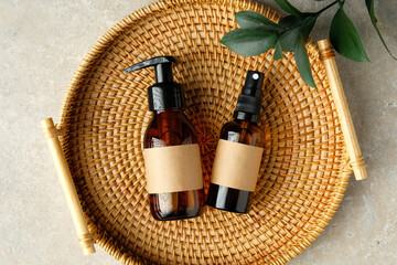 Set of amber glass bottles of natural cosmetics for personal hygiene in rattan tray. SPA organic beauty products top view.