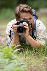 male photographer laying on the grass focusing camera